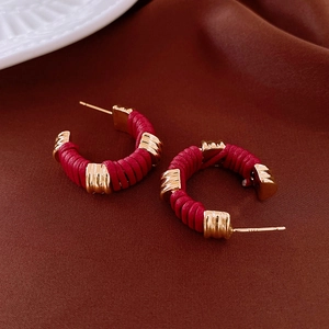 Close-up of S925 silver stud detail on red leather wrapped hoop earrings with gold accents