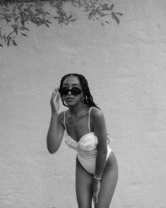 Detailed view of white one-piece swimsuit featuring 3D floral accents and thin straps