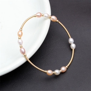 Detailed macro view of pink and white freshwater pearls on a delicate gold metal bracelet