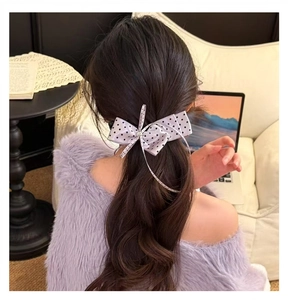 Vue détaillée d'une pince à cheveux à nœud à pois portée sur des cheveux ondulés