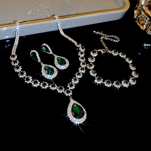 Macro shot of silver jewelry set with emerald drop stones and sparkling rhinestones