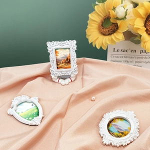 Detailed view of white baroque resin picture frames on elegant pink silk with sunflowers