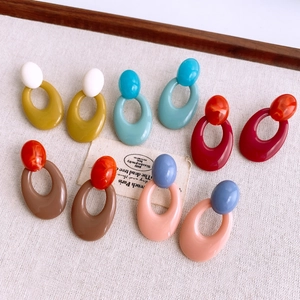 Flat lay of retro geometric acrylic earrings in various colors on textured fabric