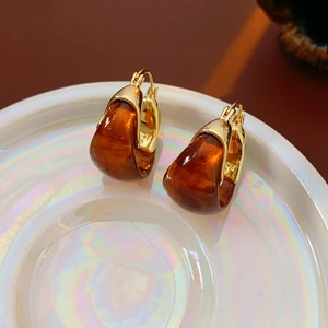 Macro shot of amber resin earrings with gold metal clasp on a holographic white display