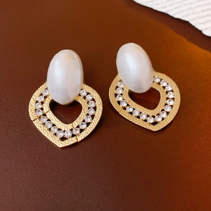 Luxurious gold heart earrings with faux pearls and rhinestones on dark leather background