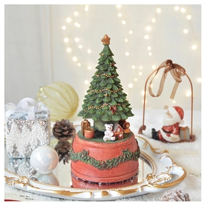 Classic Christmas tree music box on a mirrored tray with warm holiday decor and lights