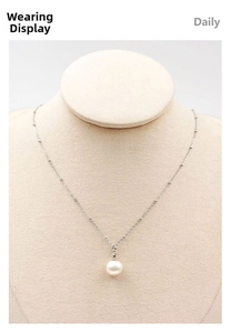 Detailed close-up of a single white pearl pendant on a thin silver beaded chain necklace