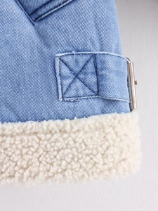 Macro view of light blue denim jacket texture with thick white sherpa lining and metal buckle