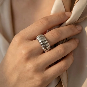 Detailed macro view of a silver wide corrugated stainless steel ring on a model's finger