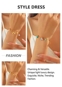 Détail du bracelet chaîne doré avec perle, nœud, éléphant bleu et breloques cœur