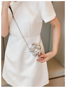 Macro detail of silver flower mini bag featuring a central pearl and fine metal chain