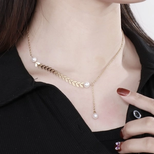 Macro view of gold leaf wheat ear necklace with elegant pearls on a female model
