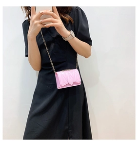 Detail of pink quilted mini crossbody bag with golden heart clasp and chain strap