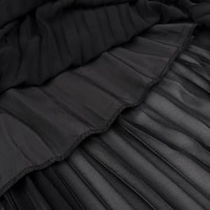 Detail of black pleated fabric showing professional stitching and layered hemline