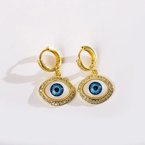 Detailed view of gold evil eye earrings with micro-paved zircons and blue resin inlay