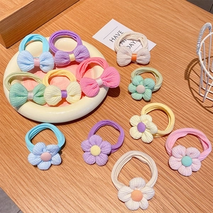 Detailed view of macaron colored bow and flower hair ties on a white ceramic plate