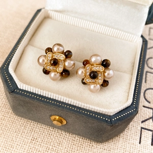 Détail de boucles d'oreilles fleurs vintage avec perles de champagne dans un écrin en velours
