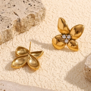 18K gold plated flower stud earrings with white crystals on stone surface