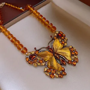 Vintage golden butterfly necklace with amber crystals and faceted beads on a jewelry box