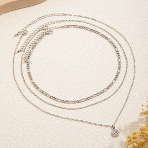 Detailed view of silver layered necklace set with Figaro chain and crystal pendant