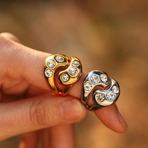 Close-up of gold and silver teardrop zircon rings worn by a model in natural light