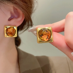 Macro detail of vintage amber resin square earrings with elegant gold metal frames