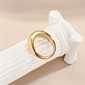 Elegant wide gold stainless steel teardrop ring displayed on a white marble pillar stand