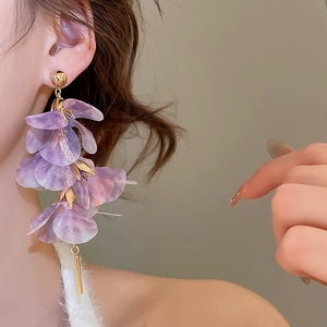 Detail of lavender mesh flower earrings with gold tassel pendants worn by a model