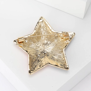 Golden star brooch back view showing alloy radial texture and secure safety pin fastener