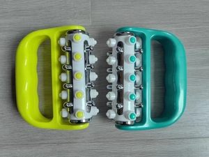 Detail of handheld rollers with dual plastic and metal massage points on wood surface