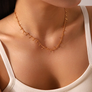 Close-up of minimalist gold-plated necklace with multiple small bar pendants on neck