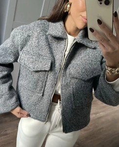 Detail of grey zip-up jacket featuring textured fabric with large utility pockets