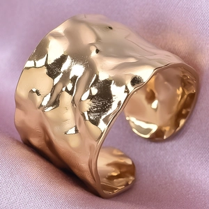 Close-up of golden wide band ring with irregular hammer texture on pink silk