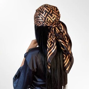 Detail of silk square scarf with geometric pattern tied around a ponytail on a model