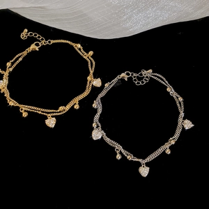 Detail of double-layer 18k gold plated bracelets with zircon heart charms on black velvet