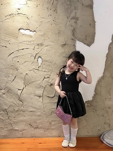 Child model in black dress styling a pink sequined handbag with a chain strap