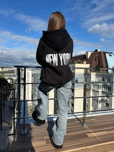 Oversized μαύρο φούτερ με τύπωμα New York στην πλάτη σε ταράτσα με θέα την πόλη