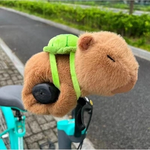 Close-up of plush Capybara snap bracelet with green turtle backpack in sunny park setting