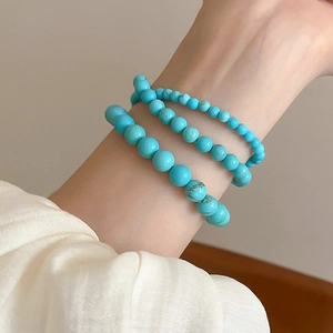 Close-up of three sky blue beaded turquoise stretch bracelets on a female wrist