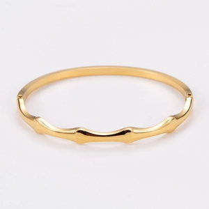 Detailed view of a golden wave pattern stainless steel bangle with polished bamboo design
