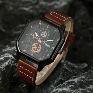 Detail of square black watch case with brown leather strap on dark stone texture
