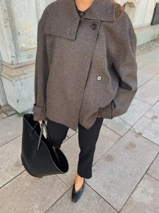 Close-up of a women's brown plaid wool coat with a large lapel and button detail