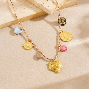 Gold charm necklace with leopard head, heart, and coin pendants on woven rope