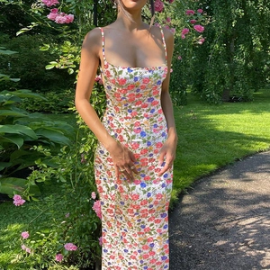 Détail d'une robe d'été fleurie à fines bretelles et dos nu dans un décor naturel de jardin