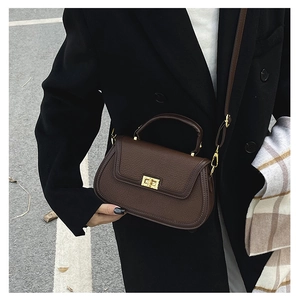 Détail du cuir grainé marron foncé et du fermoir rotatif doré de ce sac à main chic