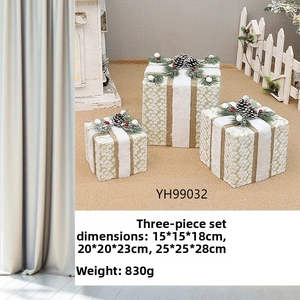 Detailed view of three-piece champagne gold Christmas gift boxes with pine cones and white ribbons