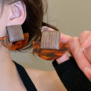 Detail view of retro geometric earrings with wood square and amber acetate textures