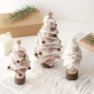 Three sizes of wool felt Christmas tree ornaments on wooden bases in a warm cozy setting