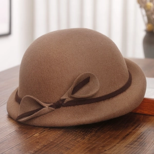 Detail of wool cloche hat with brown decorative band and side bow on wooden table