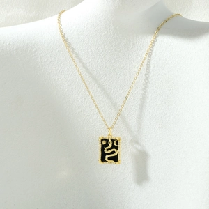 Macro detail of gold tarot pendant featuring a snake pattern with zircon accents on a chain